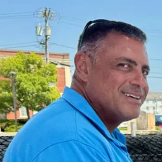 Capt. David Grunes in a blue polo shirt, smiling over his shoulder