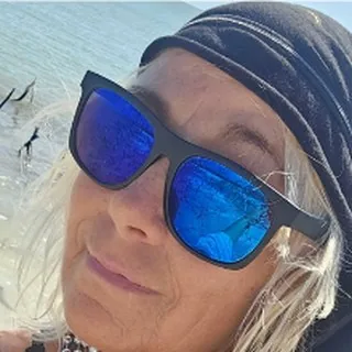 Capt. Jamie in a gray head wrap and blue mirrored sunglasses with the water behind her