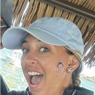 First Mate Veronica in a light blue cap under the tiki roof, mid laugh