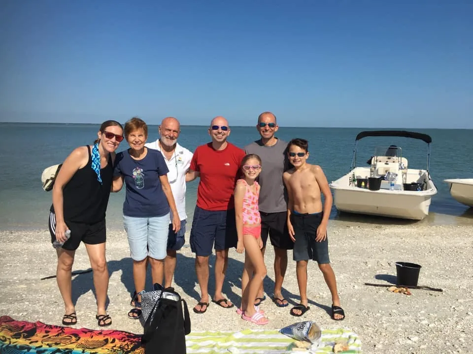 A group poses on the beach beside the boat in the morning